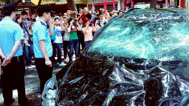 People take pictures of a Japanese car damaged during a Chinese protest last month