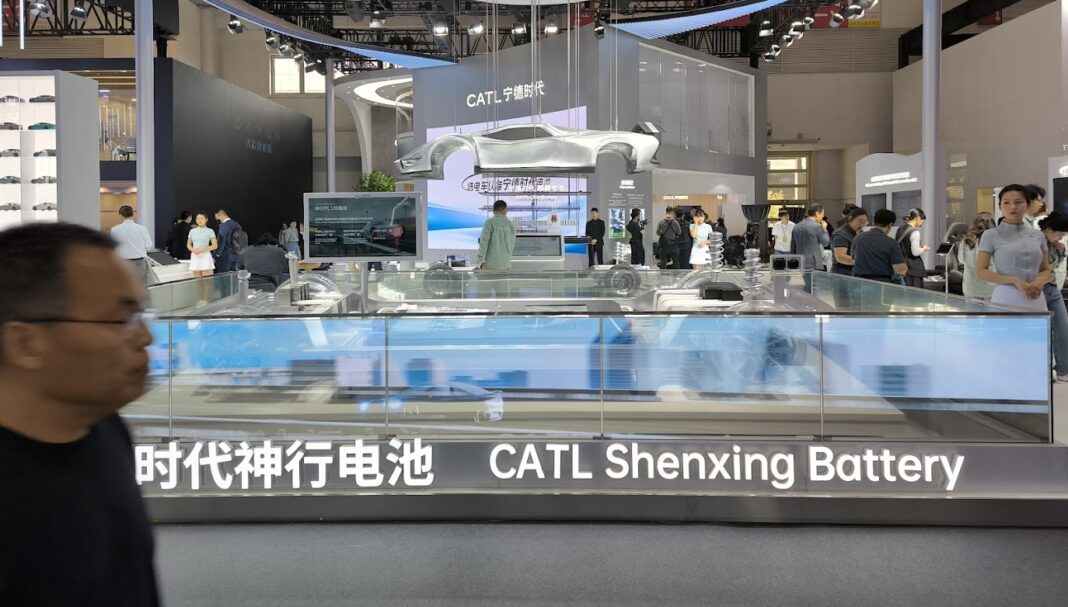 A display booth showcasing the CATL Shenxing Battery for 2025, featuring a suspended car model and surrounded by visitors at an exhibition or trade show.